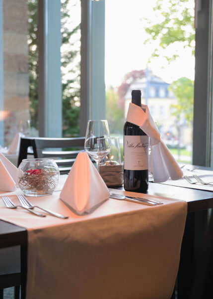 Gedeckter Tisch mit einer Flasche Rotwein im Restaurant des Welcome Hotel Bad Arolsen